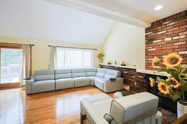 living room with vaulted ceiling, a baseboard radiator, light hardwood / wood-style flooring, and plenty of natural light