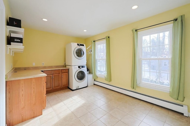 washroom with stacked washer / drying machine, a healthy amount of sunlight, cabinets, and a baseboard heating unit