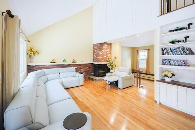 living room featuring lofted ceiling, a wood stove, a baseboard heating unit, built in features, and light hardwood / wood-style floors