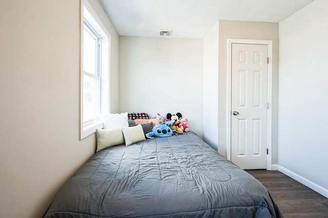 bedroom featuring wood finished floors, visible vents, and baseboards