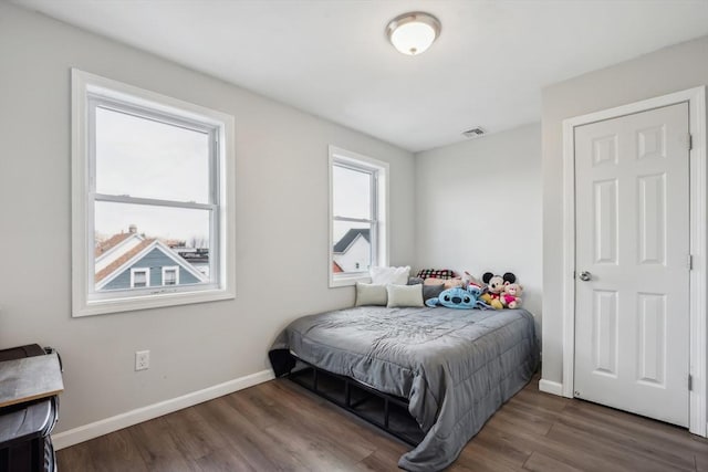 bedroom featuring visible vents, baseboards, and wood finished floors