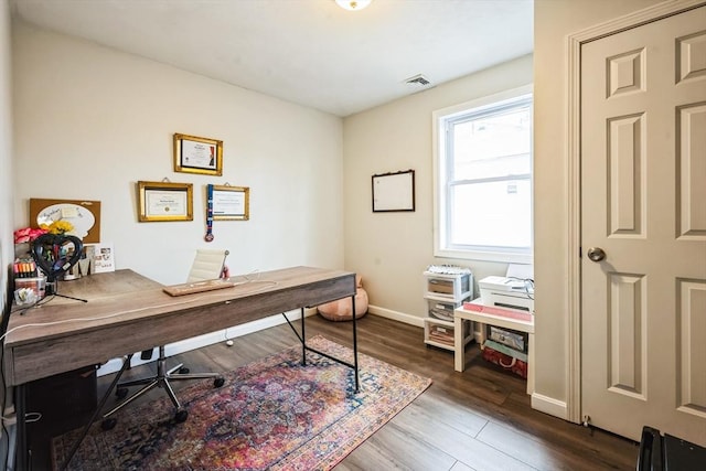 office space featuring wood finished floors, visible vents, and baseboards