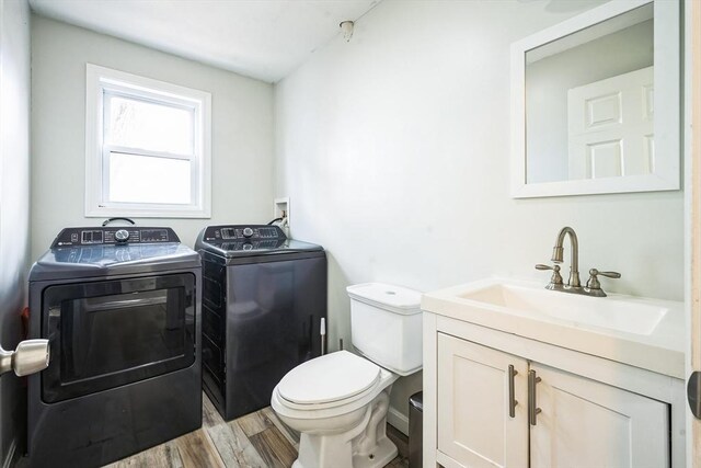 bathroom with vanity, toilet, wood finished floors, and independent washer and dryer