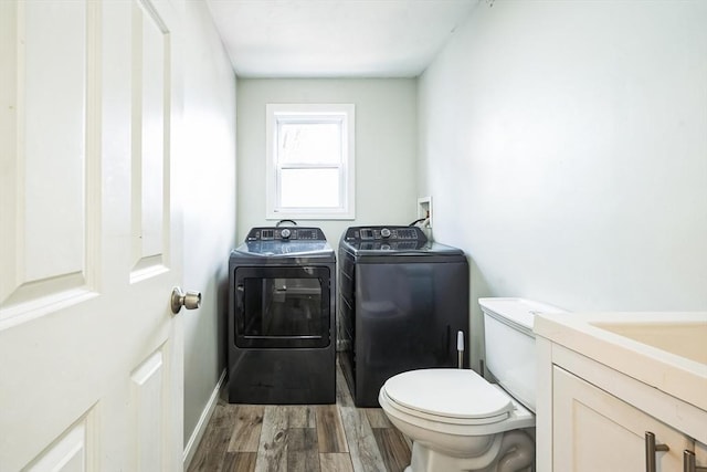 half bathroom with washer and dryer, baseboards, toilet, and wood finished floors