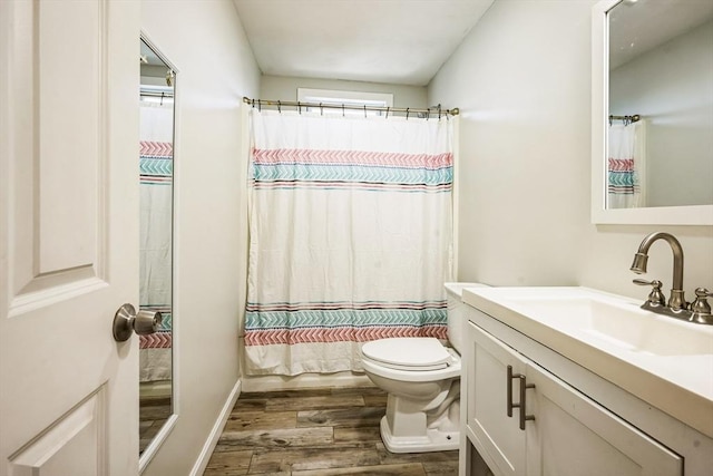 bathroom with toilet, vanity, and wood finished floors