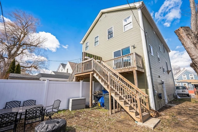 back of house with stairway, a deck, outdoor dining space, and fence