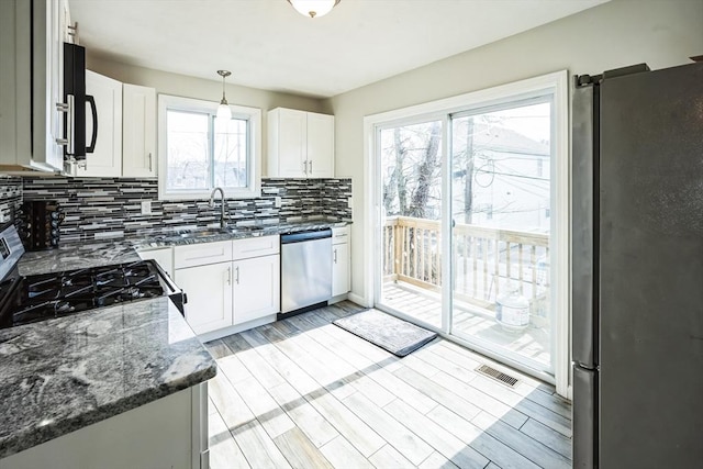 kitchen with wood finish floors, visible vents, dark stone countertops, tasteful backsplash, and stainless steel appliances