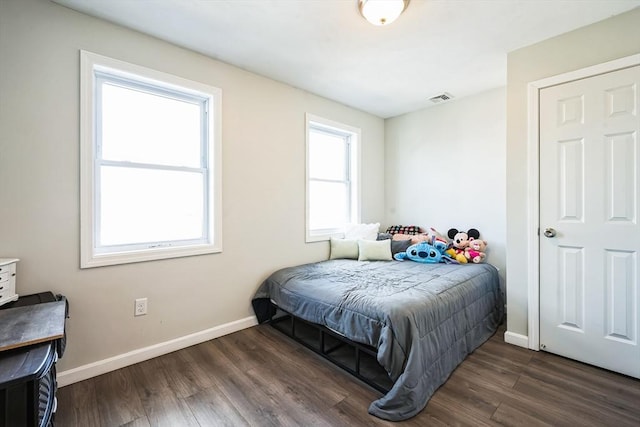 bedroom featuring visible vents, baseboards, and wood finished floors