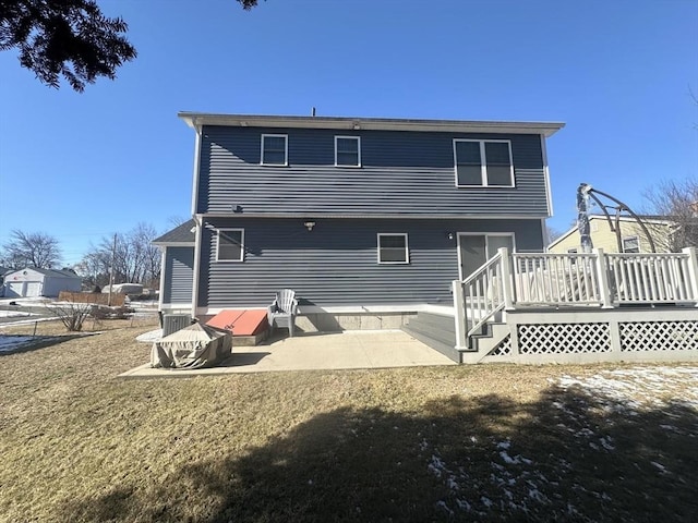 rear view of house featuring a deck, a patio area, and a lawn