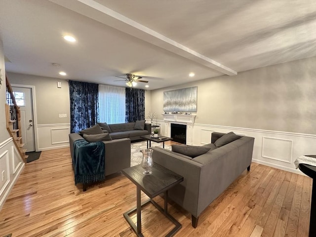 living room with beamed ceiling, ceiling fan, and light wood-type flooring