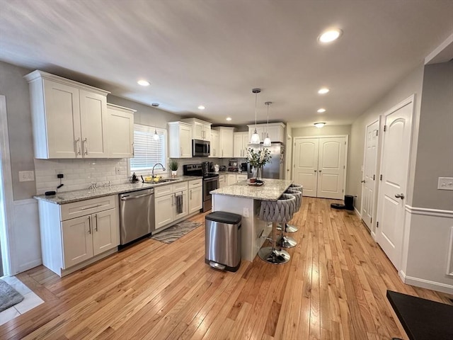 kitchen with sink, decorative light fixtures, a center island, appliances with stainless steel finishes, and white cabinets