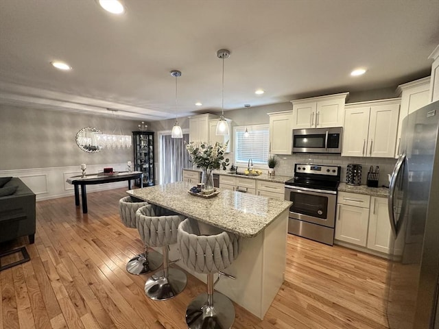 kitchen with stainless steel appliances, a kitchen island, pendant lighting, and white cabinets