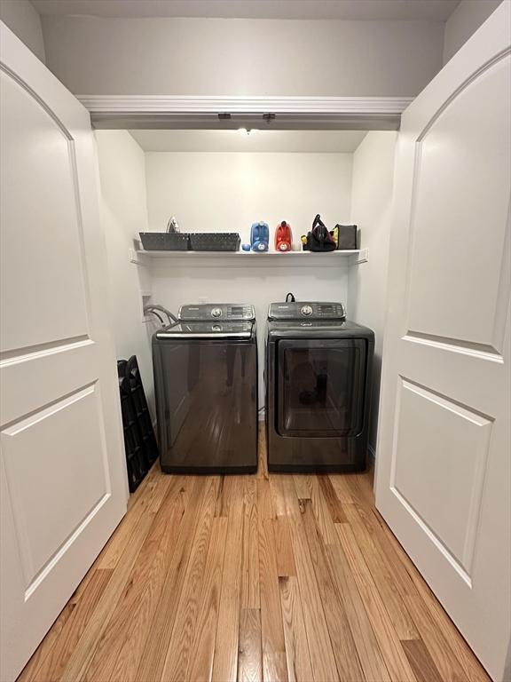 laundry room with washing machine and clothes dryer and light wood-type flooring