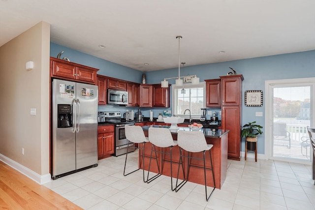 kitchen with stainless steel appliances, a kitchen breakfast bar, pendant lighting, a center island, and light wood-type flooring