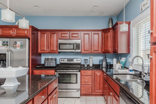 kitchen featuring stainless steel appliances, dark stone counters, sink, and pendant lighting