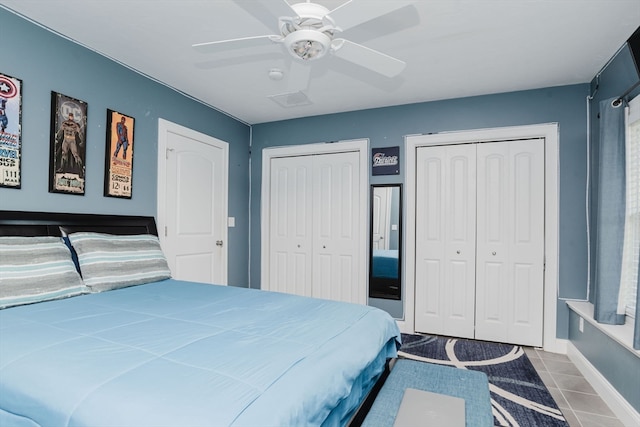 bedroom featuring ceiling fan, tile patterned floors, and multiple closets