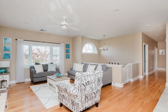 living room featuring light hardwood / wood-style floors and ceiling fan with notable chandelier