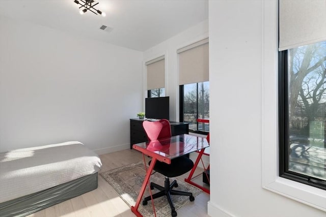 bedroom with multiple windows and light hardwood / wood-style flooring