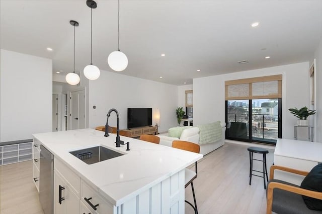 kitchen with white cabinetry, an island with sink, dishwasher, pendant lighting, and sink