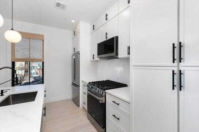 kitchen featuring tasteful backsplash, pendant lighting, sink, appliances with stainless steel finishes, and white cabinets