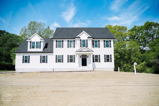 colonial-style house featuring roof with shingles