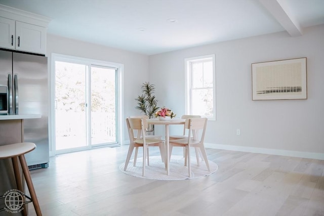 dining area with light wood finished floors, beam ceiling, and baseboards