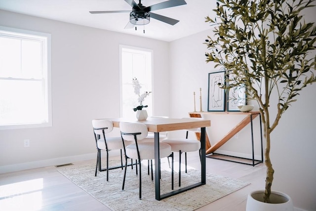 dining space featuring wood finished floors, baseboards, and ceiling fan