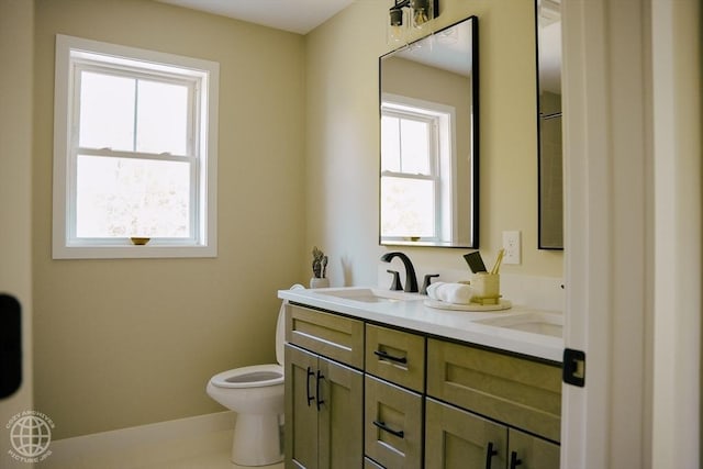 bathroom featuring toilet, double vanity, and baseboards