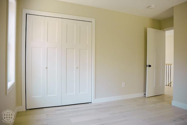 unfurnished bedroom with light wood-style floors, baseboards, and a closet