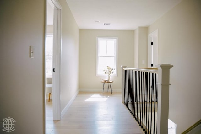 hallway with an upstairs landing, light wood-type flooring, and baseboards