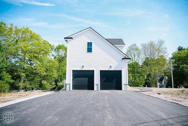 view of property exterior featuring an attached garage and asphalt driveway