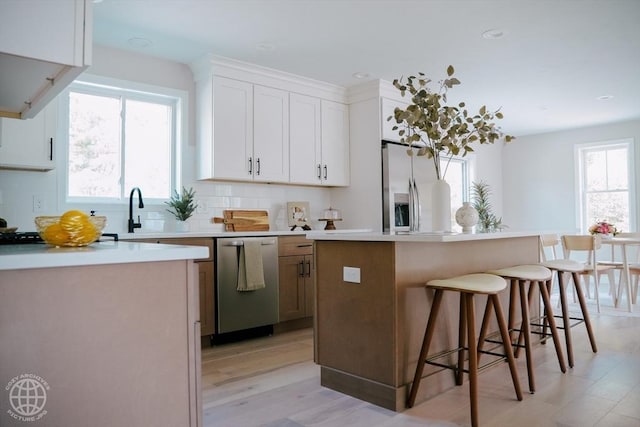 kitchen with appliances with stainless steel finishes, a breakfast bar area, a center island, tasteful backsplash, and light wood finished floors