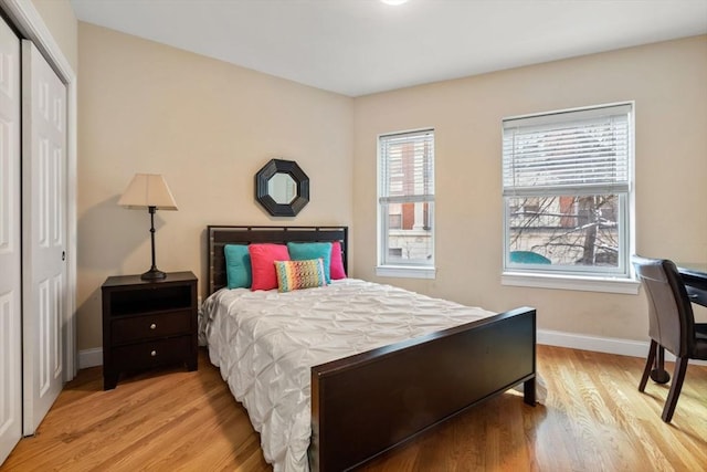 bedroom with light wood-style floors, baseboards, and a closet