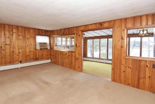 carpeted empty room featuring baseboard heating, wood walls, a wall unit AC, and a chandelier