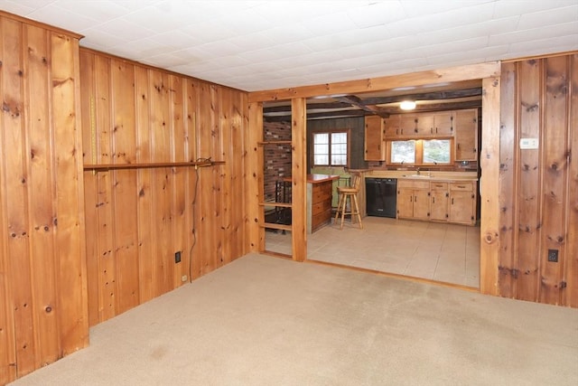 interior space with dishwasher, carpet floors, sink, and wood walls