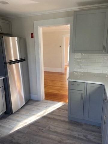 kitchen featuring gray cabinetry, decorative backsplash, light hardwood / wood-style floors, and stainless steel refrigerator