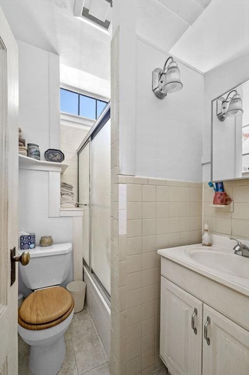 full bathroom featuring toilet, tile walls, vanity, enclosed tub / shower combo, and tile patterned flooring