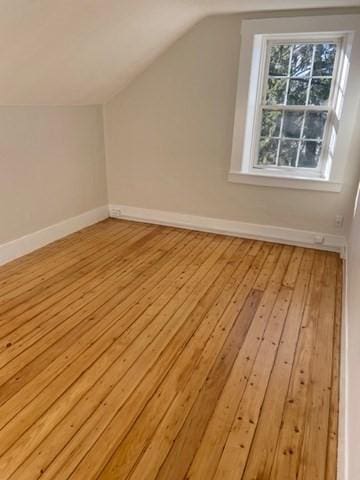 additional living space with lofted ceiling and light hardwood / wood-style flooring