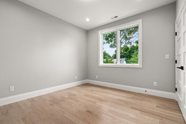 unfurnished room with light wood finished floors, visible vents, and baseboards