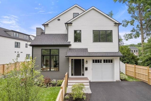 view of front of home featuring aphalt driveway, an attached garage, roof with shingles, and fence