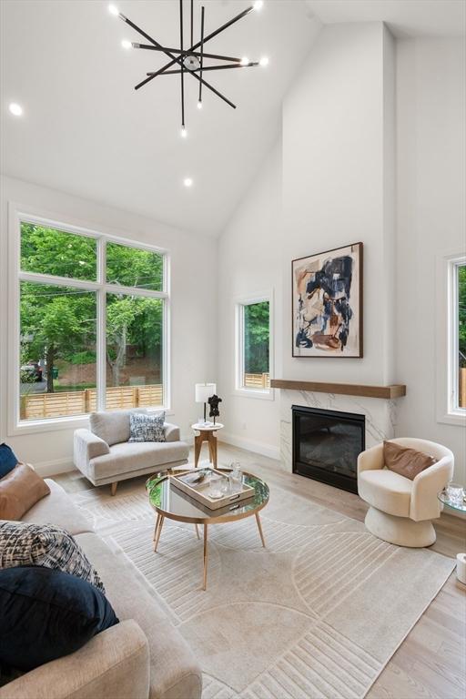 living room featuring a wealth of natural light, a fireplace, high vaulted ceiling, and wood finished floors