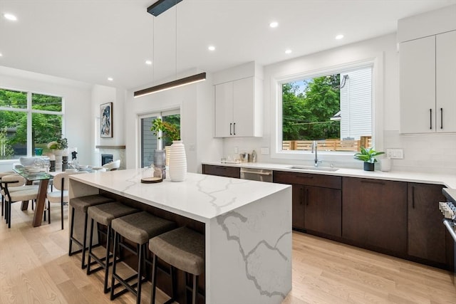 kitchen with dark brown cabinetry, a kitchen breakfast bar, light wood-type flooring, and a sink