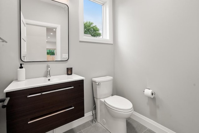 half bath with baseboards, toilet, vanity, and tile patterned flooring