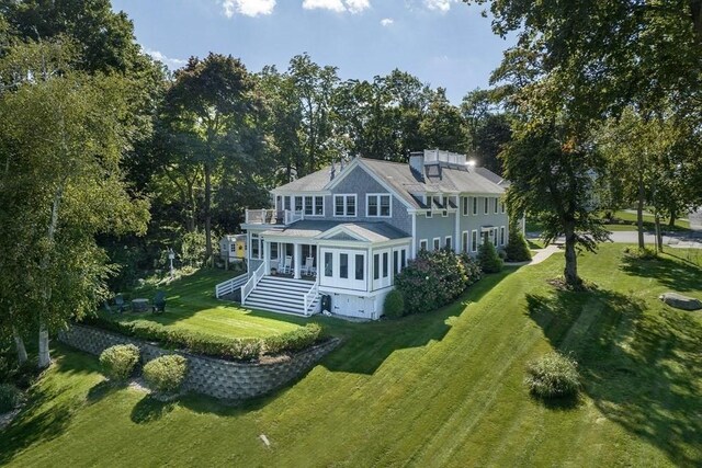 back of property featuring a balcony and a lawn