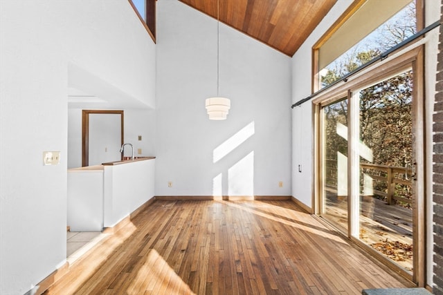 unfurnished living room with light wood-type flooring, sink, high vaulted ceiling, and wooden ceiling