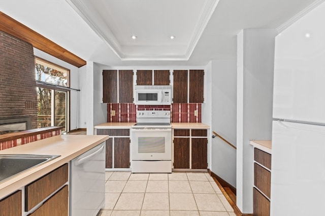 kitchen featuring tasteful backsplash, a raised ceiling, white appliances, a fireplace, and light tile patterned flooring