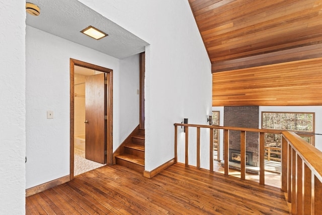 corridor with hardwood / wood-style floors, lofted ceiling, and wooden ceiling