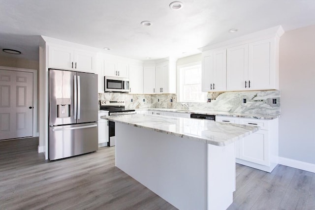 kitchen featuring stainless steel appliances, a kitchen island, white cabinetry, and light wood-type flooring