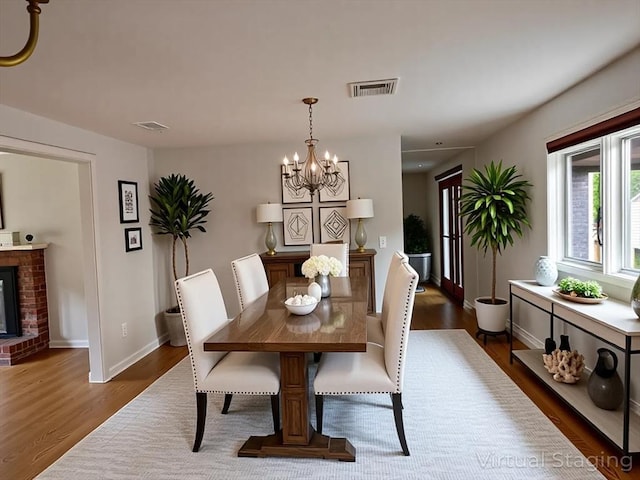 21 Friends Ln, Dennis, MA 02660 - dining area with dark wood finished floors, a chandelier, and a fireplace