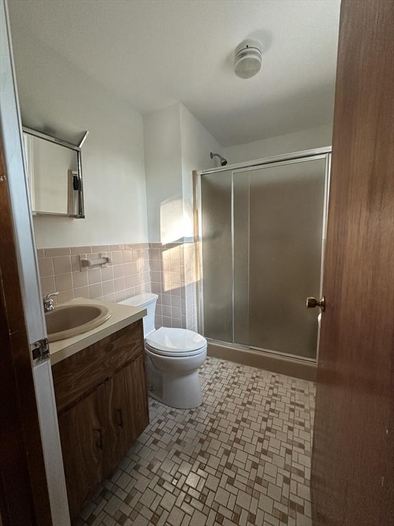 21 Friends Ln, Dennis, MA 02660 - full bath with vanity, a stall shower, tile walls, and a wainscoted wall